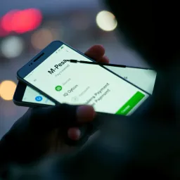 Mobile phone screen showing M-Pesa payment option for funding IQ Option account securely in Kenya